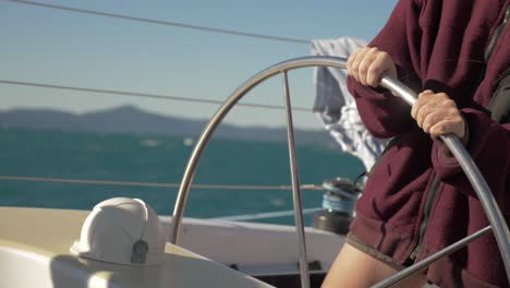 cropped shot of a woman controlling a boat's wheel while cruising in whitsunday island, queensland, australia