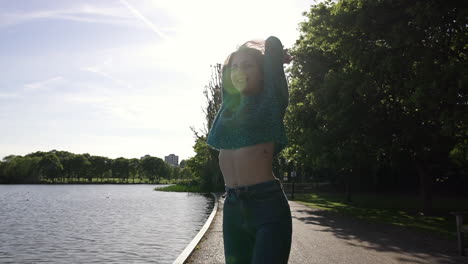 beautiful italian girl walking peacefully and spinning in a tranquil park wearing a shimmery sweater in london, united kingdom