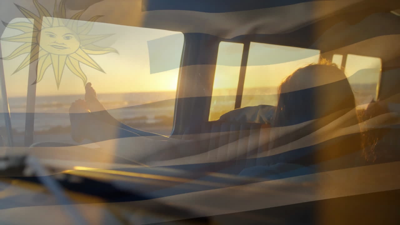 Uruguay flag with sun symbol overlaying sunset view from car window
