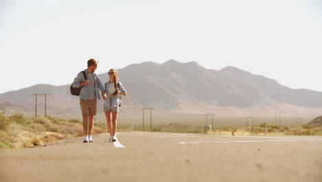 couple on vacation hitchhiking along road shot on r3d