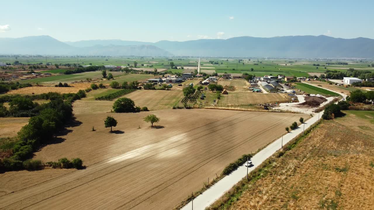 Aerial view of rural landscape with fields, road, and mountains