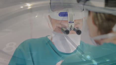 animation of clock hands ticking fast over caucasian male and female surgeon operating