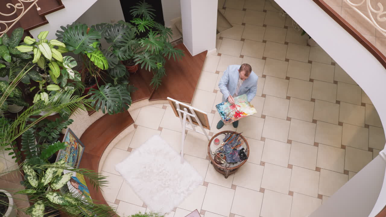 컬러 패을 가진 아티스트는 스튜디오에서 작업합니다. 미술 마스터는 워크에서 그림을 그리는 데 영감을 얻습니다. 집에서 전문적인 예술 용품을 가진 남자.