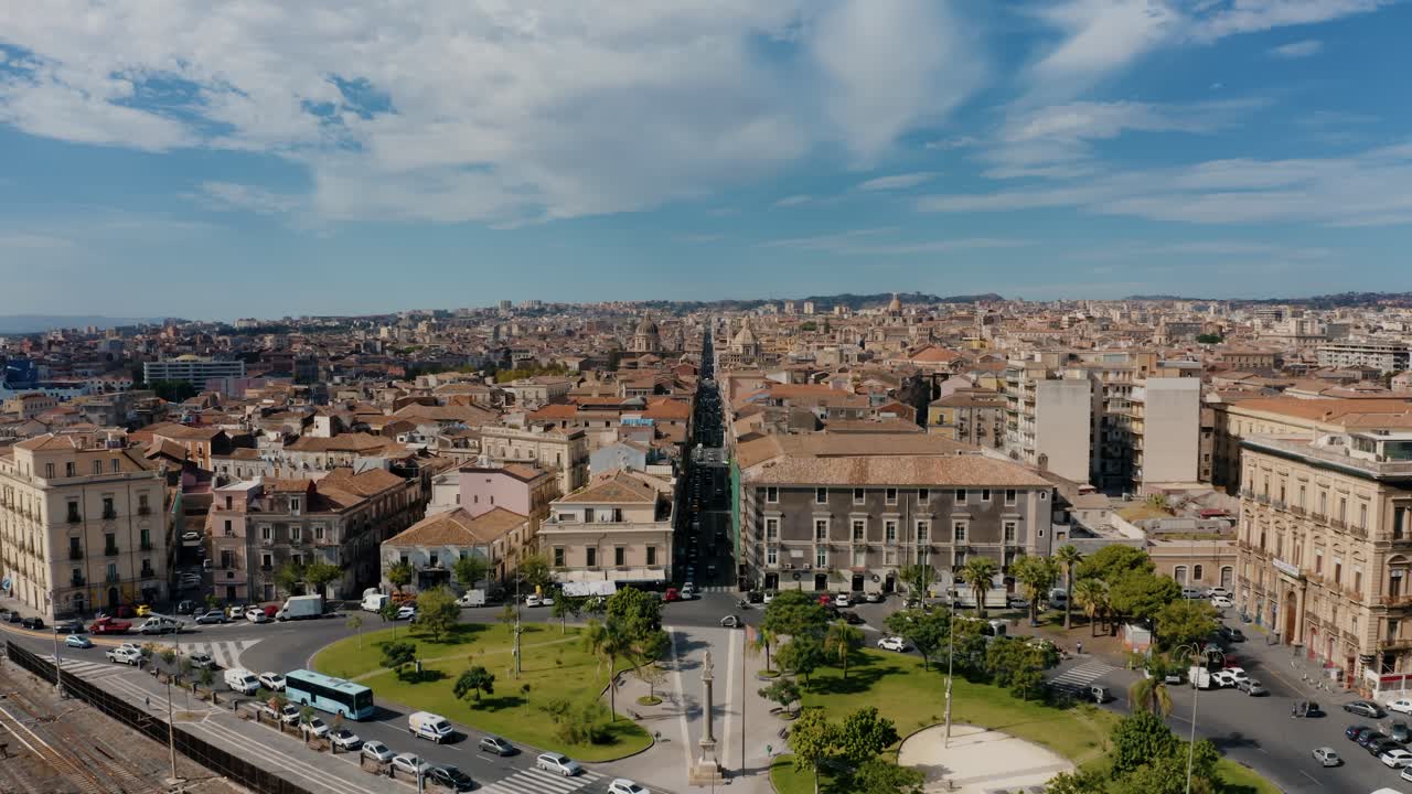 Aerial view of Piazza Martiri della Liberta in Catania. Drone flying into the city above long straight street. UNESCO World Heritage Site in Sicily.