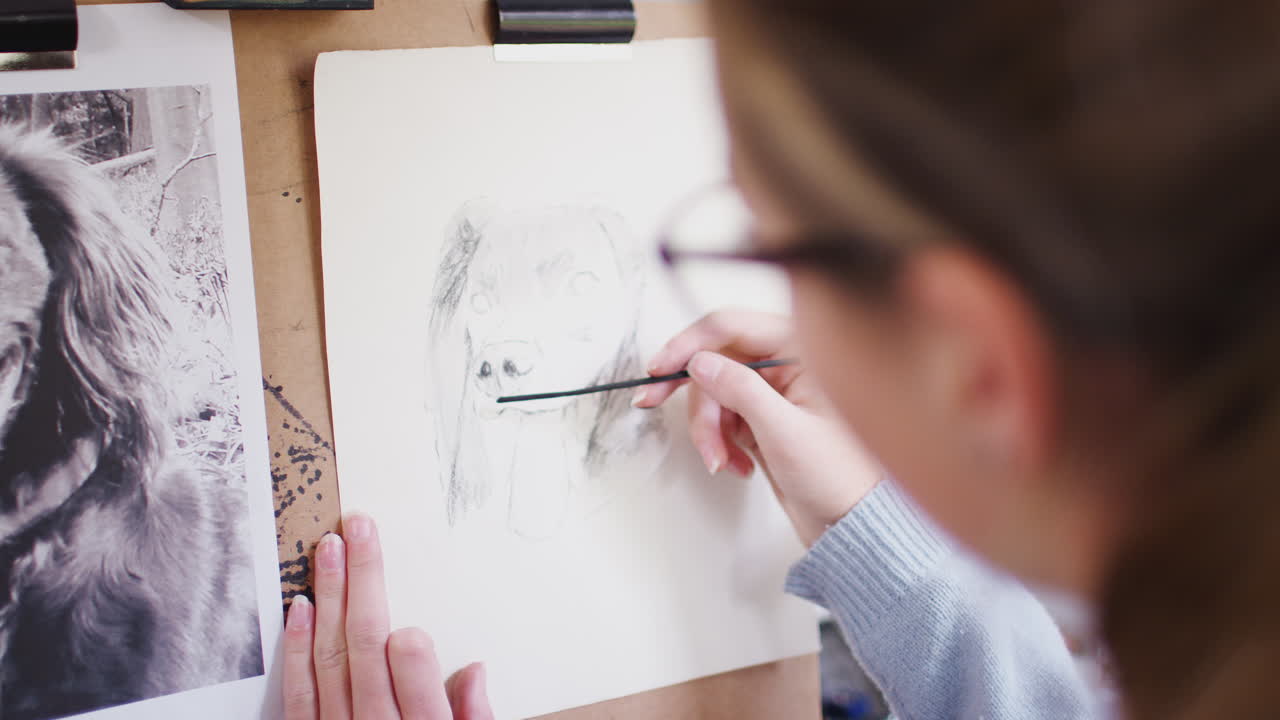 십대 여성 예술가 가 석탄 에 있는 사진 에서 개 의 그림 을 그리는 좌석 에 앉아 있다