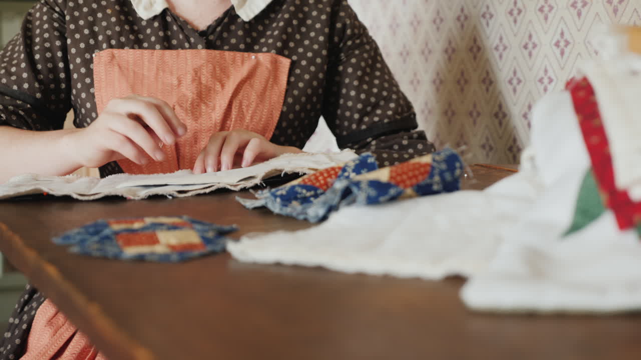 A Woman In An Antique Dress From The Time Of The Development Of America Is Engaged In Needlework