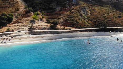 glistening blue waters and grassy hill in agia kiriaki island in kefalonia - panning aerial shot