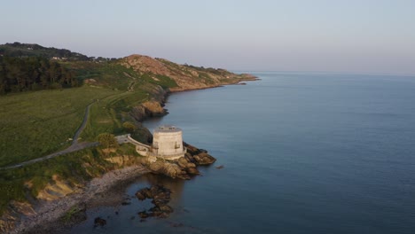 Irish-Coastal-Elegance:-Aerial-Journey-around-Martello-Tower-Sutton-in-Howth,-Ireland,-during-a-Serene-Evening-with-Howth-Summit-Views