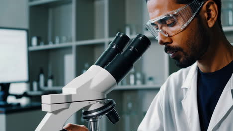 scientist conducting research and taking notes in a laboratory with a microscope