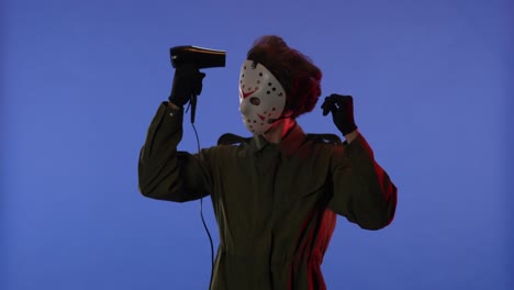 man in white mask drying hair with hair dryer on blue background with red neon light image of maniac man in white mask drying hair with hair dryer on blue background with red neon light image of maniac jason voorhees from friday 13 halloween celebration concept
