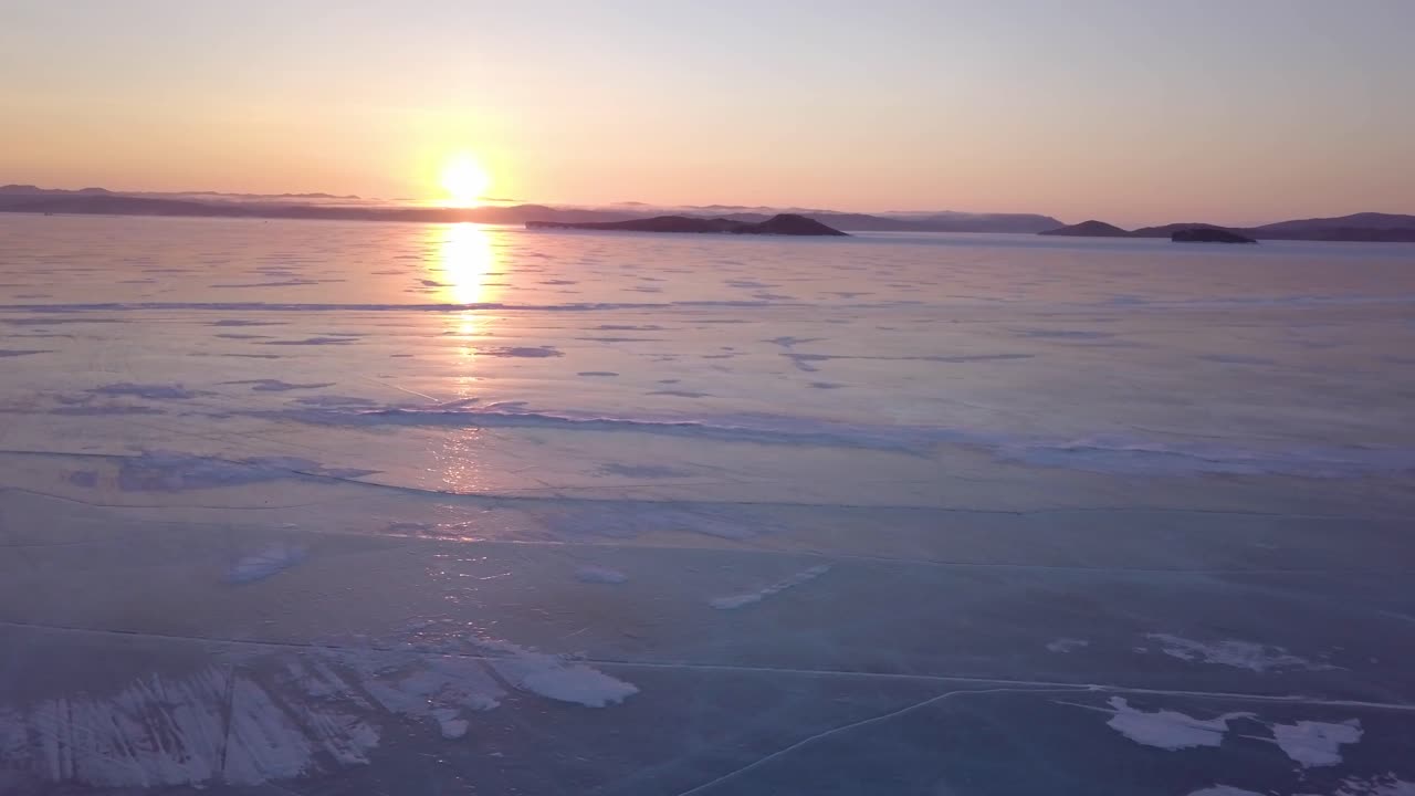 멋진 일몰과 함께 겨울에 유명한 바이칼 호수인 러시아의 서리 물 위를 낮게 날고 있는 드론