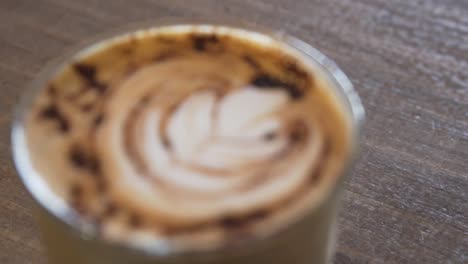 cafe latte art in glass set on a wooden table - close up shot