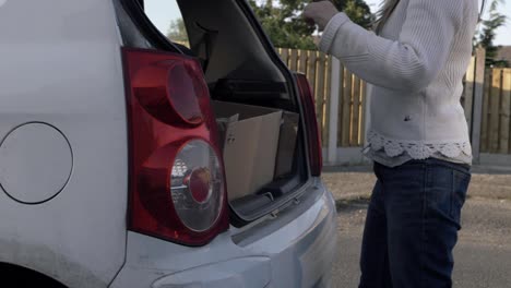 mujer cerrando el maletero del coche plano amplio