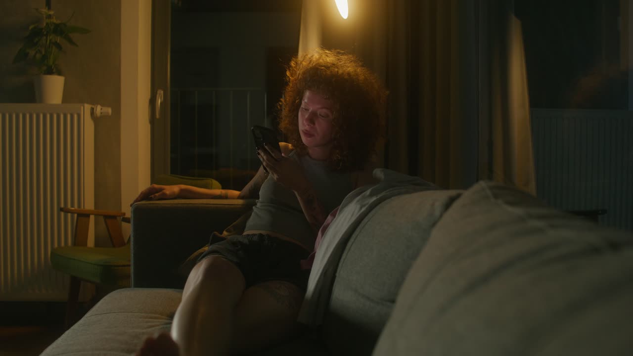 mujer usando un teléfono inteligente por la noche en el sofá
