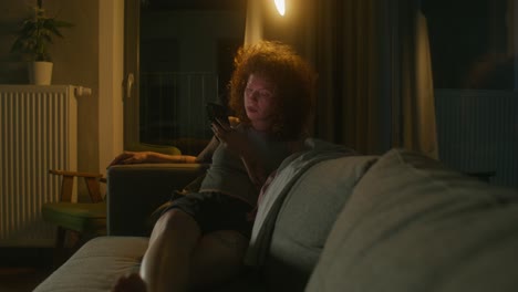 woman using smartphone at night on the couch