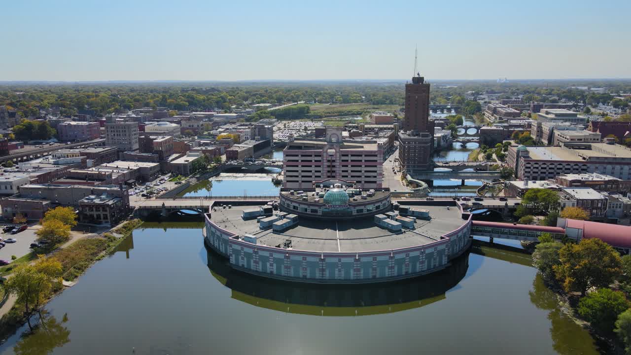 Drone footage capturing downtown Aurora, IL, a Chicago suburb in the Chicagoland area, near the river, buildings, and the Metra train line. Crane Down Left Day S