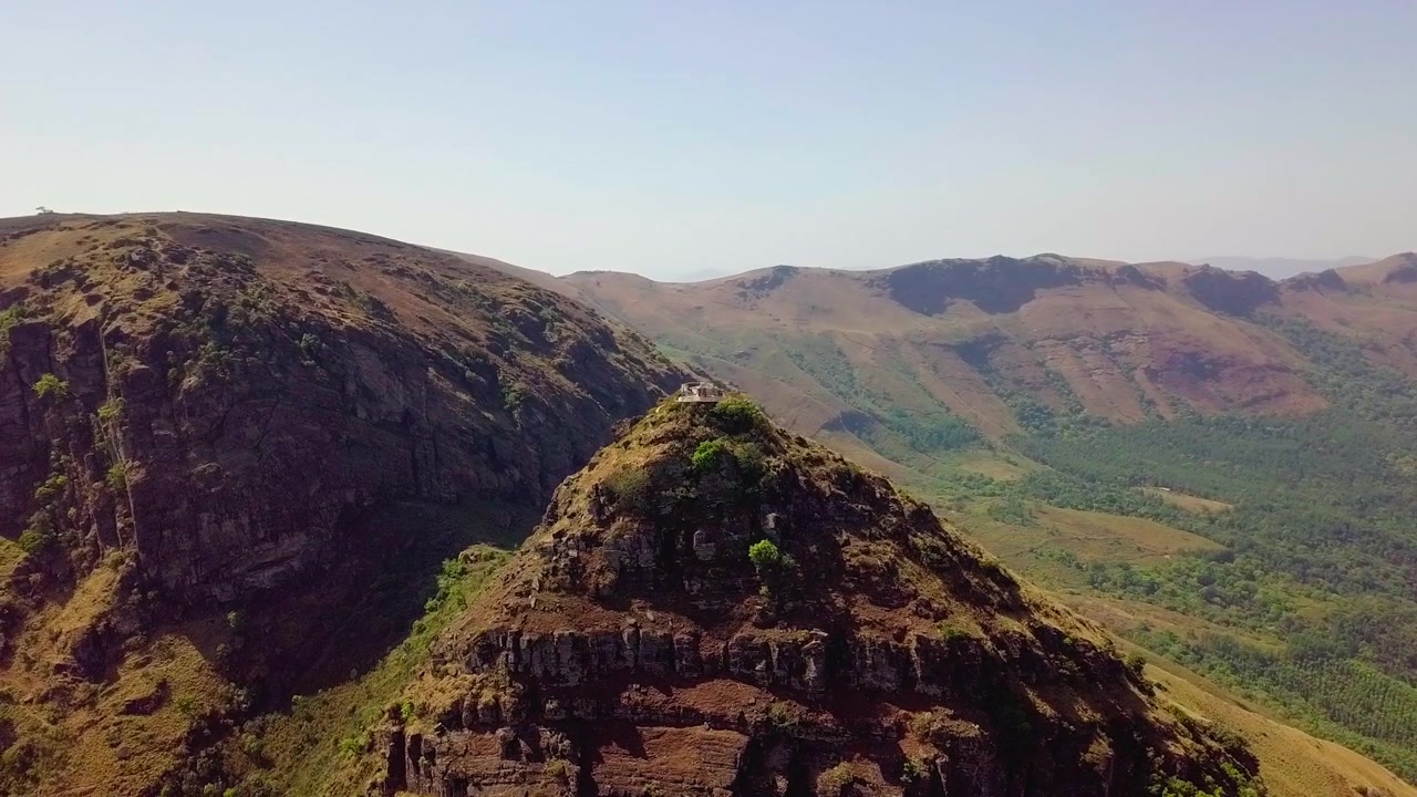La catena montuosa di Chikmagalur sotto cieli sereni con cime rocciose e valli verdi, vista aerea.