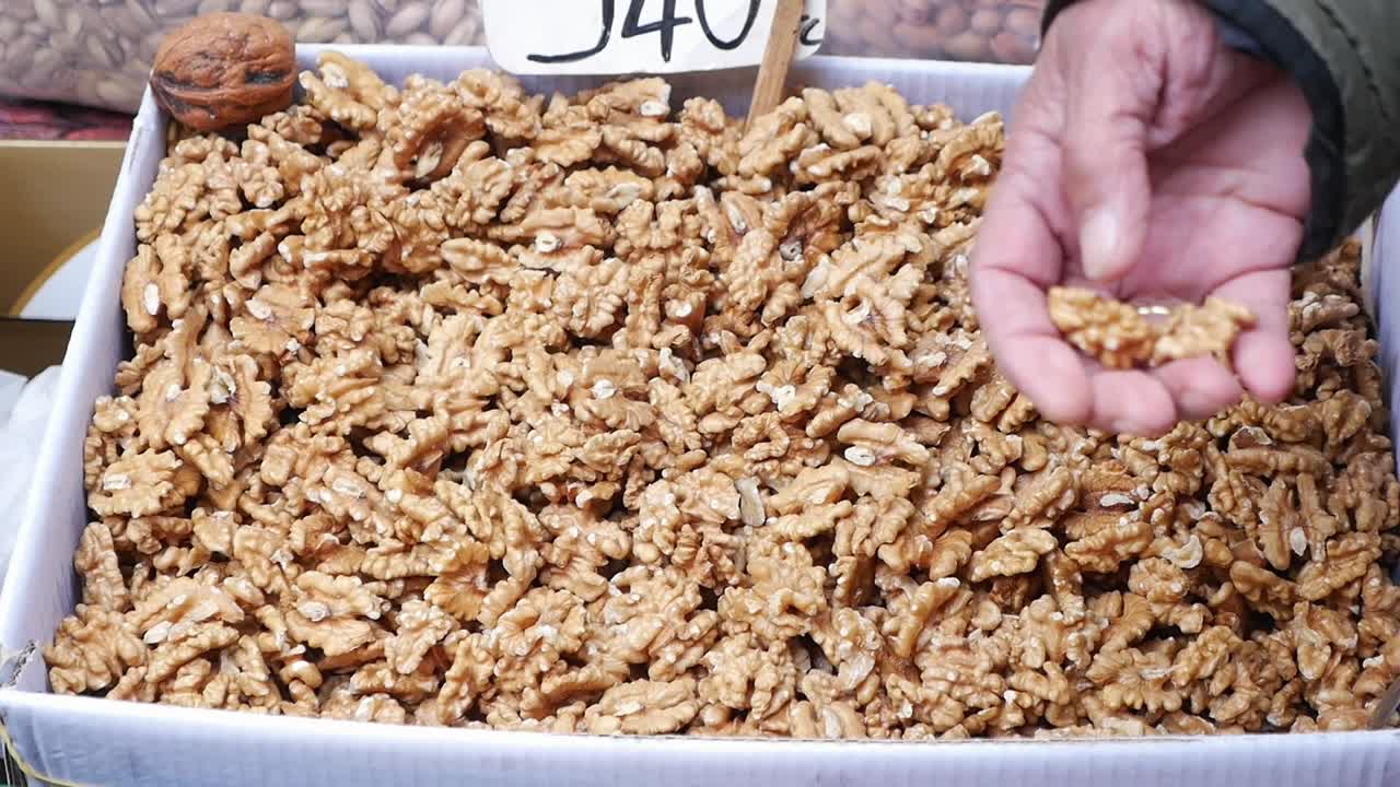 Hand Picking Fresh Shelled Walnuts from a Market Box