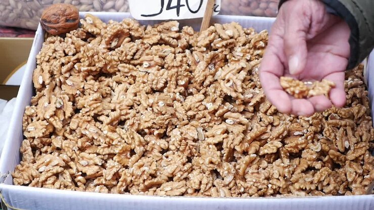 Hand Picking Fresh Shelled Walnuts from a Market Box