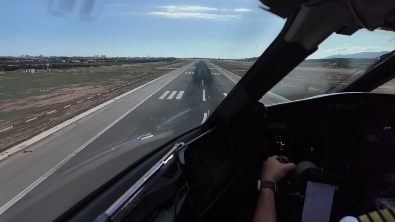 A cockpit view with the hands of a pilot grasping and piloting the flight controls of a jet airplane in a real time landing with crosswind and turbulence.