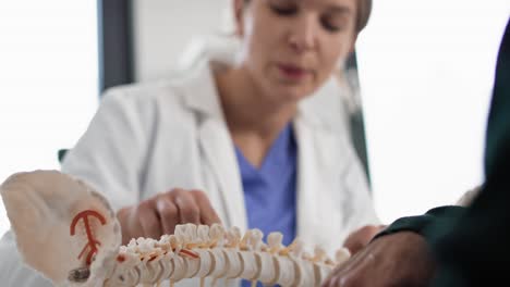 Caucasian-female-doctor-talking-with-patient-about-his-spine.