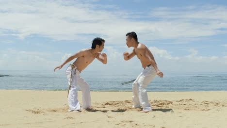 dos hombres bailando capoeira en la playa