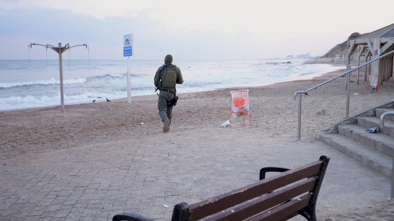 un soldado israelí completamente armado y equipado corre a lo largo de una playa temprano en la mañana