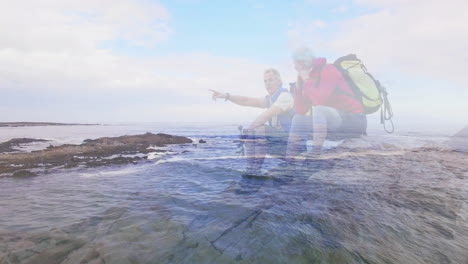 male hiker pointing at horizon on shore and female hiker observing sea with animated health chart
