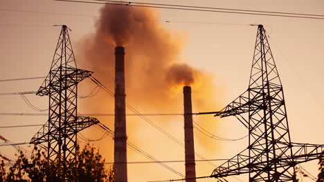 atmospheric air pollution. high voltage electric lines on the background of smoking pipes at sunset. harmful industry with dirty fumes from chimneys.