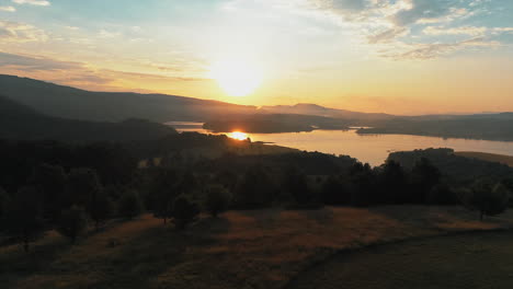 a beautiful sunrise over the mountains and a lake that reflects the sunrise, there is a low fog next to the lake