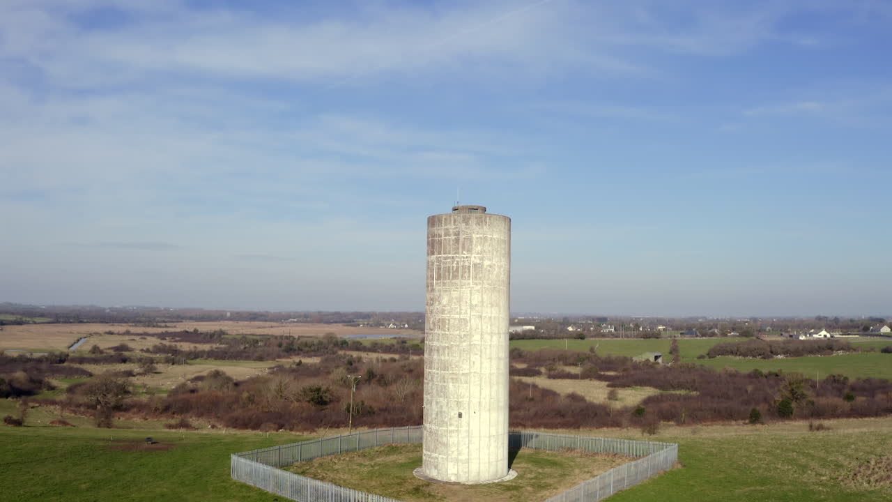 Aerial ascent of Clarinbridge water tower against a clear blue sky, showcasing the structure and surrounding area in Galway