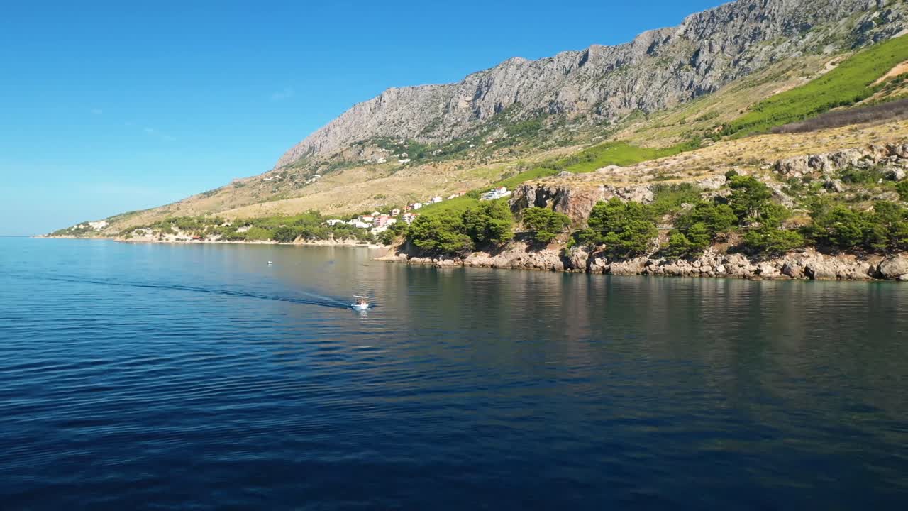 Aerial drone footage of a passing boat on a sea near a bay in Mimice, Croatia