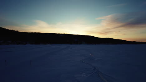 Flying-drone-above-a-frozen-lake-in-canada-at-golden-hour