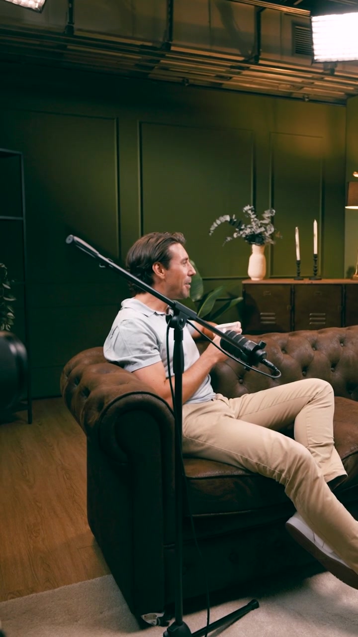 Uomo seduto su un divano in pelle durante la registrazione di un podcast