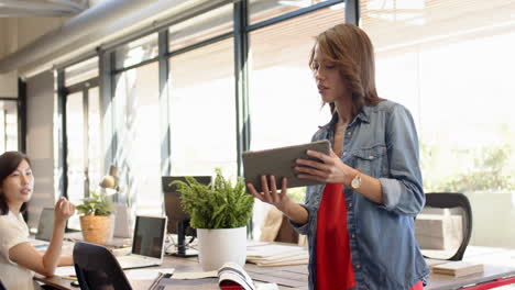 using tablet, woman discussing interior design project in modern office setting