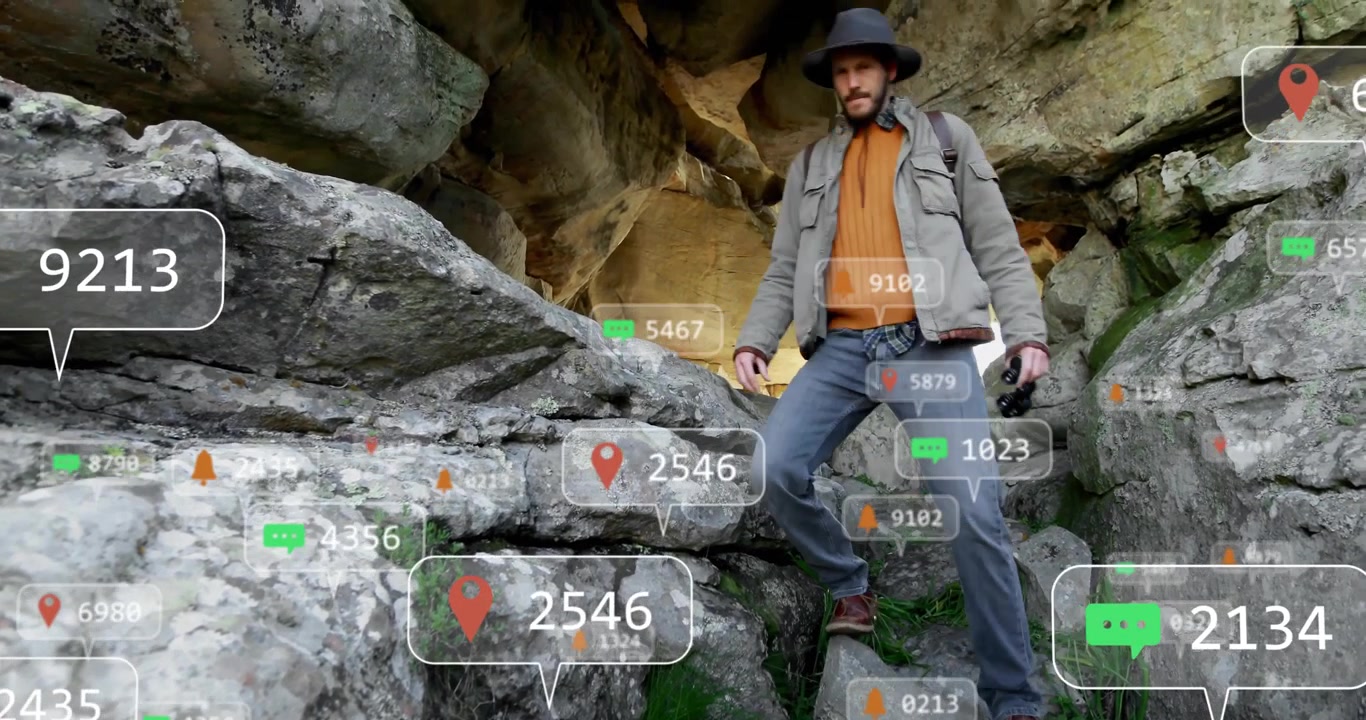 Esploratore che si ferma su una sporgenza rocciosa di una grotta, attivando icone di notifica fluttuanti durante una demo tecnologica.