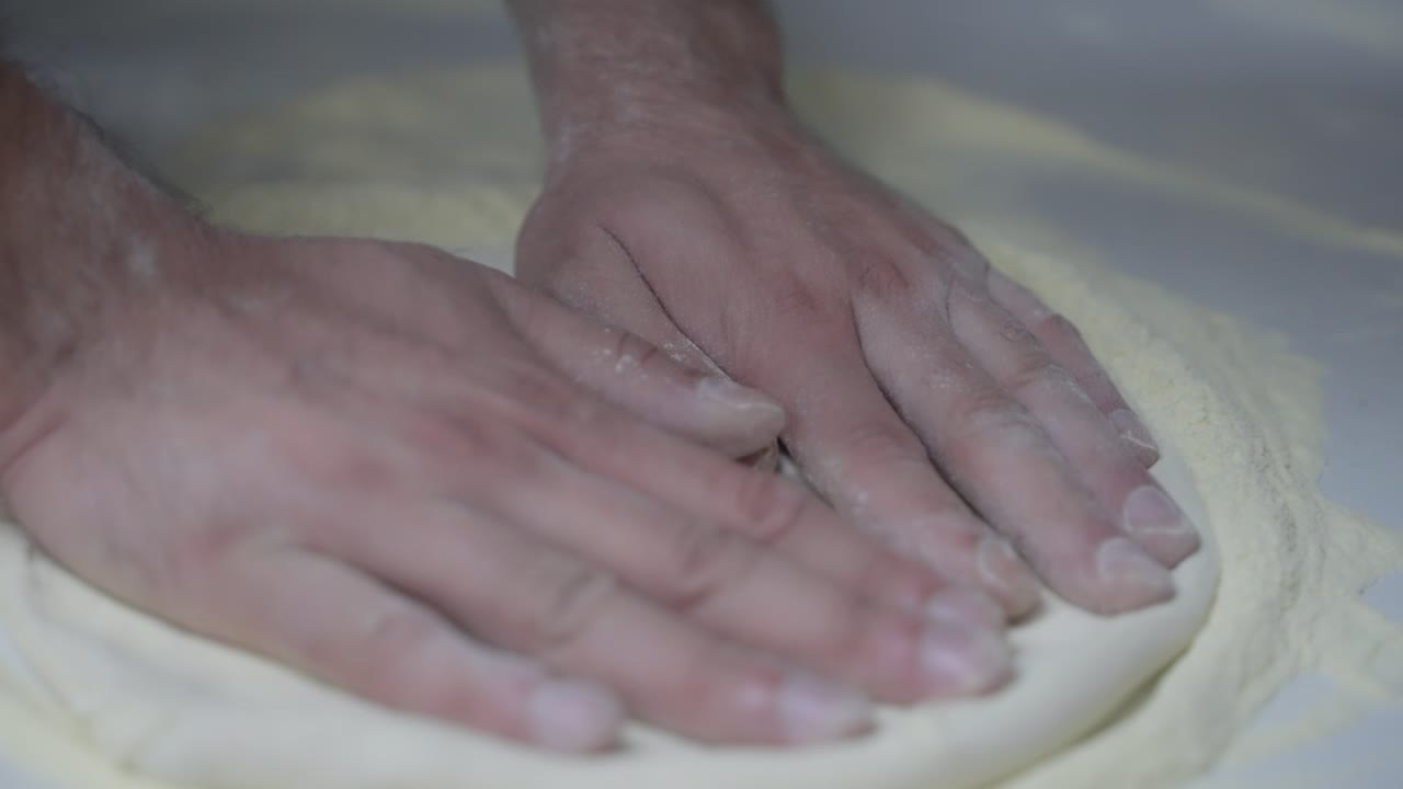 Primo piano in slow motion dello stendere l'impasto della pizza a mano