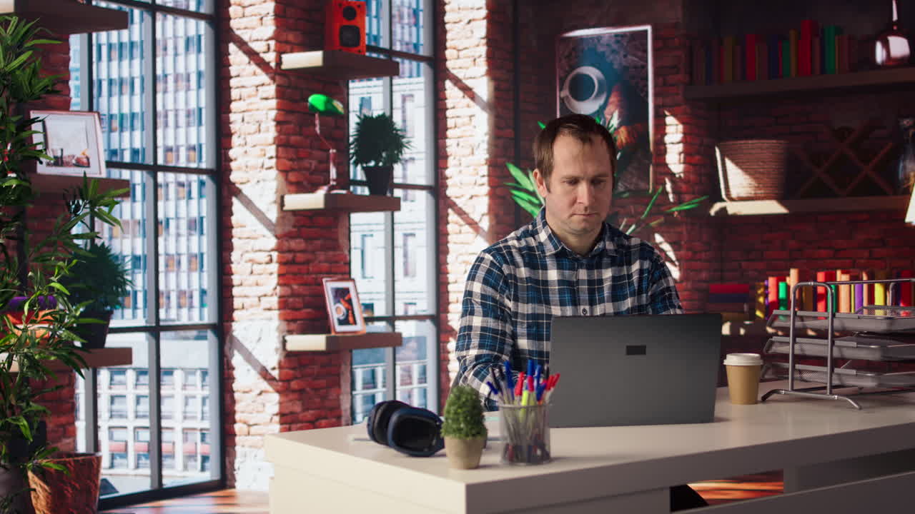 Man seated at home office desk using laptop, checking emails