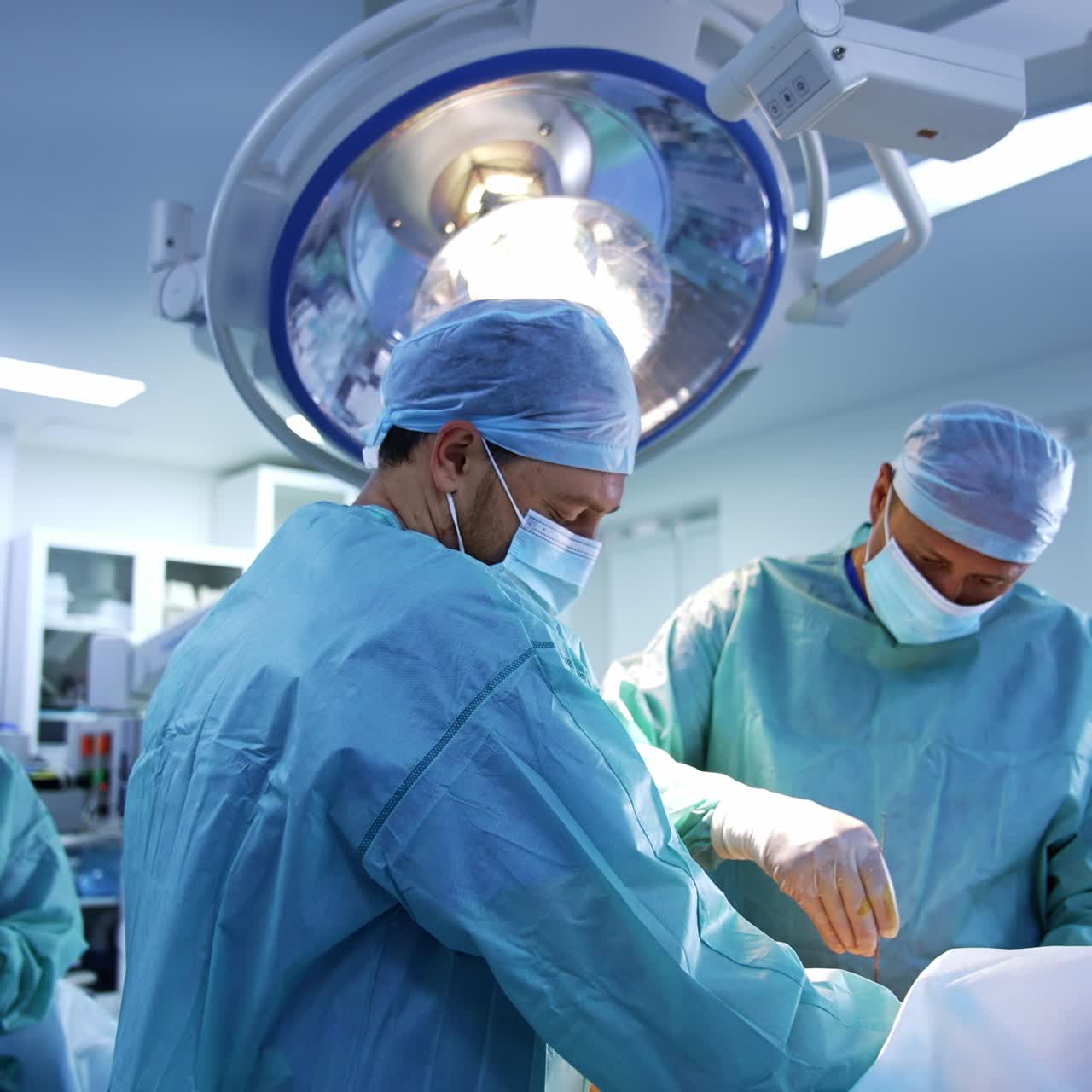 Team medico che lavora in collaborazione in sala operatoria. Il chirurgo primario usa il bisturi durante l'operazione. Attrezzatura moderna sullo sfondo