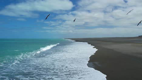 Cámara-Lenta-Aérea-Baja-De-Gaviotas-Sobre-Olas-Rompientes-Del-Hermoso-Océano-Pacífico-Sur-De-Color-Turquesa