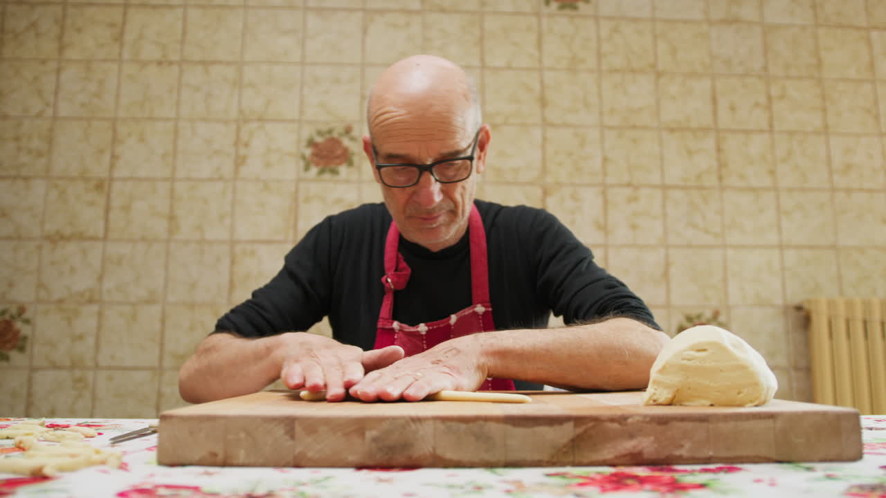 Älterer Mann bereitet gekonnt traditionelle hausgemachte kalabrische Pasta zu.