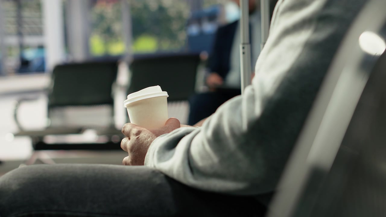 Close-up de turista com café em terminal de ônibus durante espera matinal