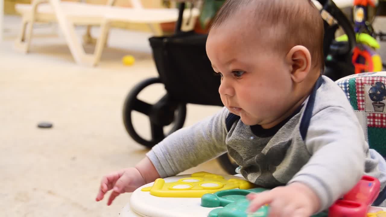 An adorable baby playing in his walker while drooling on his sweater