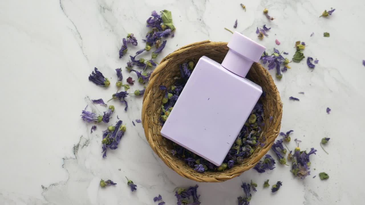 botella de perfume púrpura con flores de lavanda secas