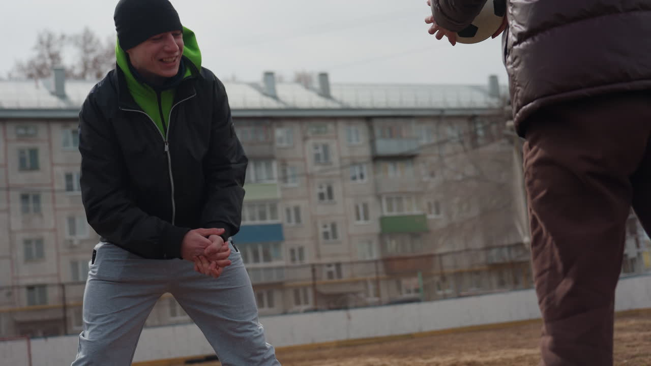 노련한 코치가 도시에서 비공식적인 겨울 축구 연습 중에 젊은 학생을 차분하게 지도하는 겨울 날씨 속에서 강사가 어린 선수를 코칭하는 도시 배경의 멘토가 청소년을 지도합니다.