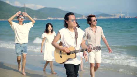 young asian adults walking on beach