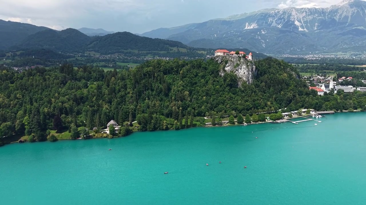 Ripresa con drone del Castello di Bled su una collina sopra acque alpine azzurre in una giornata estiva, Slovenia