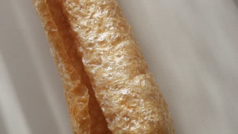 crunchy pork rind, close-up shot highlighting texture and shape of the snack