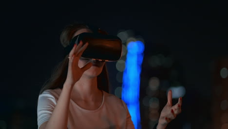 A-young-girl-in-virtual-reality-glasses-in-a-large-metropolis-simulates-work-in-the-program-game-virtual-reality-interface.-The-concept-of-augmented-reality