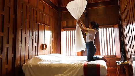 person installing mosquito net over bed